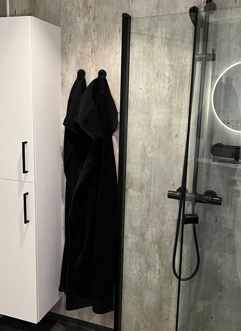 Innfellbare dusjvegger i sort matt, sort takdusj og praktisk høyskap i hvitt